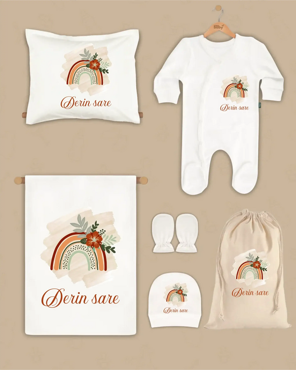 Gepersonaliseerde Newborn Cadeauset met regenboogdesign en naam Derin sare, bestaande uit een deken, kussen, boxpakje, hoed en handschoenen.