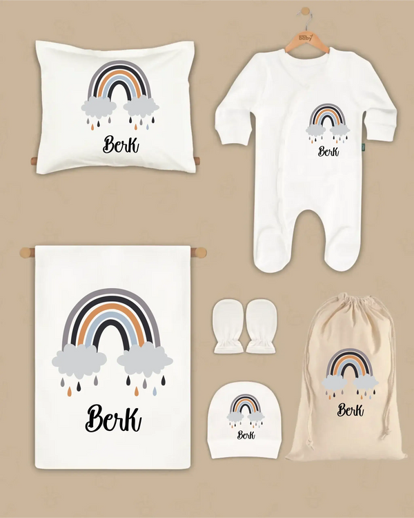 Gepersonaliseerde 6-delige newborn cadeauset met regenboog en naam, inclusief deken, kussen, boxpakje, hoed en handschoenen.
