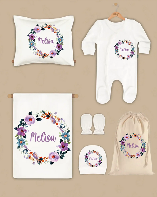 Gepersonaliseerde newborn cadeauset met bloemenkrans en naam Melisa, inclusief deken, kussen, boxpakje en hoed.