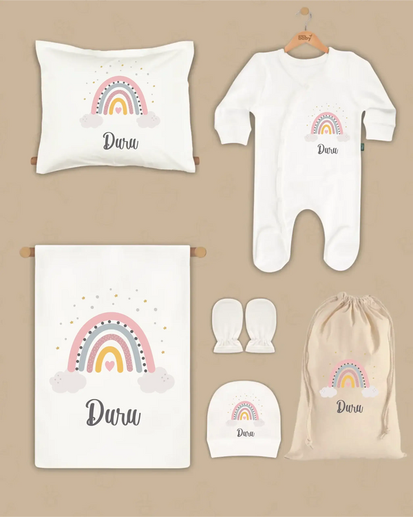 Gepersonaliseerde 6-delige newborn set met rainbow design en naam Duru op kussen, dekentje, boxpakje, hoed en handschoenen.