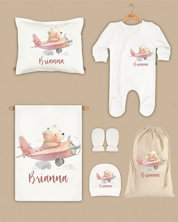 Gepersonaliseerde 6-delige newborn cadeauset met vliegtuigbeer en naam, inclusief deken, kussen, boxpakje, hoed en handschoenen.