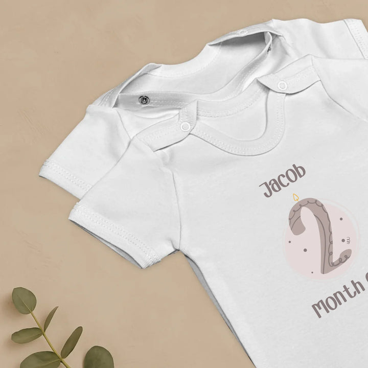 Gepersonaliseerde baby romper set met naam en maandnummer in pastel kleur voor mijlpalen.