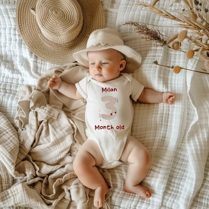 Baby wearing a personalized vintage romper with a hat, showcasing month three milestone.