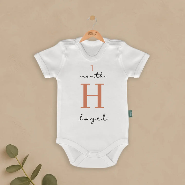 Personalized baby romper design featuring '1 month H hazel' in modern typography.