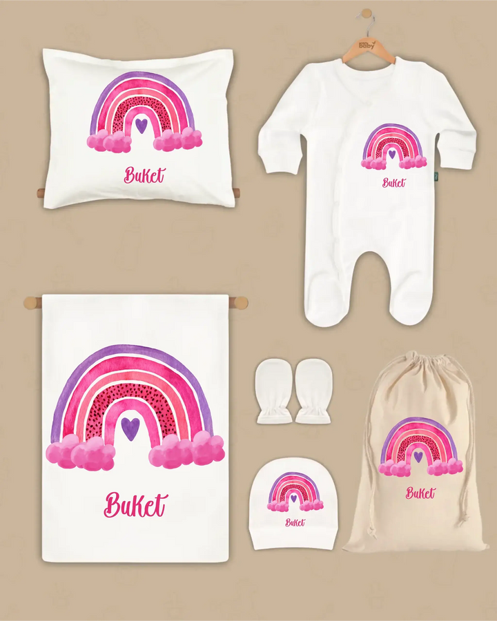 Gepersonaliseerde newborn cadeauset met regenboogdesign en naam, inclusief kussen, boxpakje, hoed en sokken.