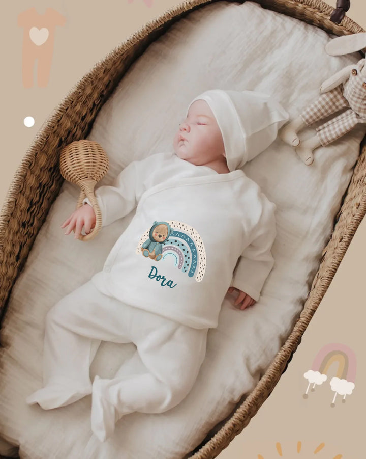 Baby in personalized white outfit with rainbow design, resting in basket. Soft and cozy organic cotton for comfort.
