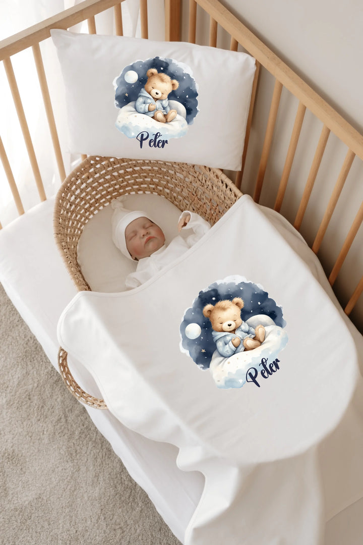 Baby sleeping in a cozy bassinet with personalized teddy bear bedding featuring the name Peter.