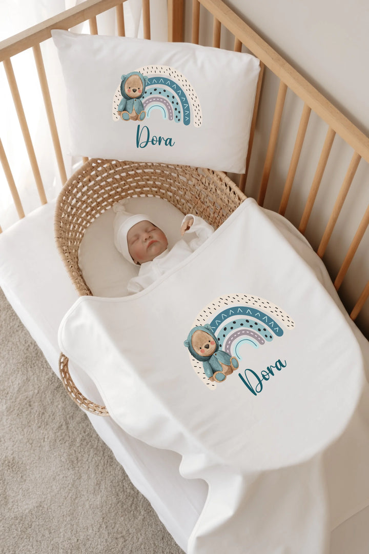 Gepersonaliseerde babyset met regenboogprint en naam in bedje, perfect voor newborns.