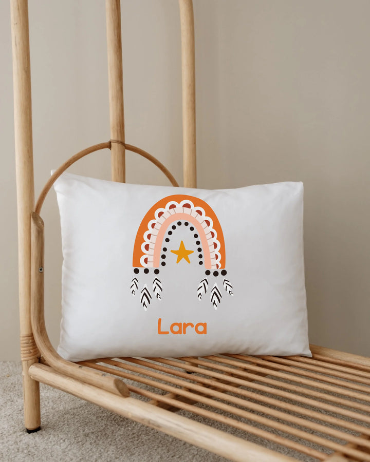 Gepersonaliseerd kussen met naam 'Lara' en oranje regenboogillustratie op een houten standaard.