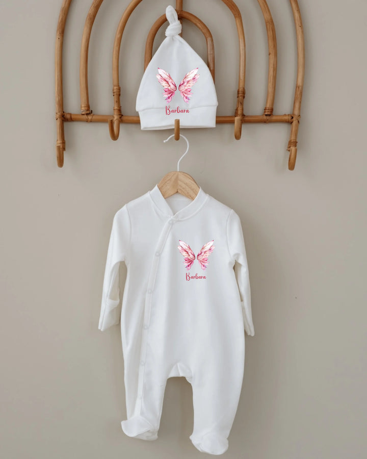 Gepersonaliseerde witte babyromper en muts met roze vlinderprint en naam, perfect als uniek cadeau.