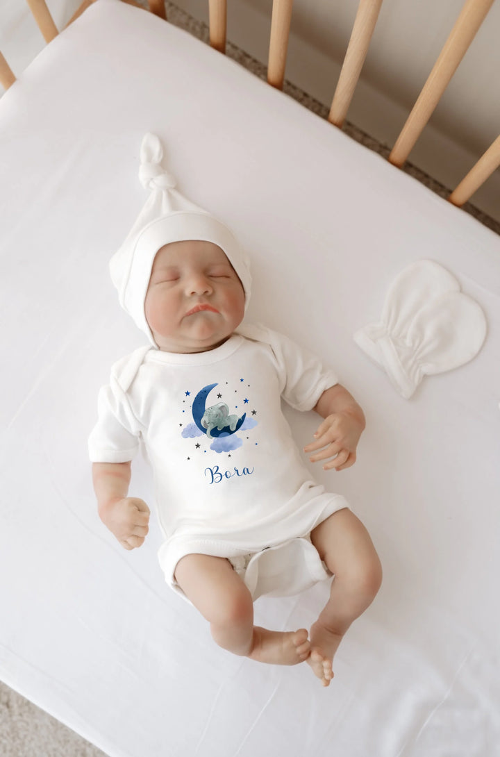 Gepersonaliseerde babyromper met blauwe olifant en maan, slaapbaby in bed met witte muts, geschikt voor newborns.