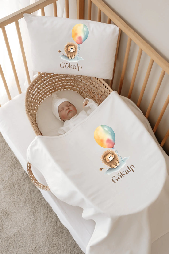 Slaapbaby in een mand met gepersonaliseerd beddengoed met een leeuw en ballon, zacht en schattig ontwerp.