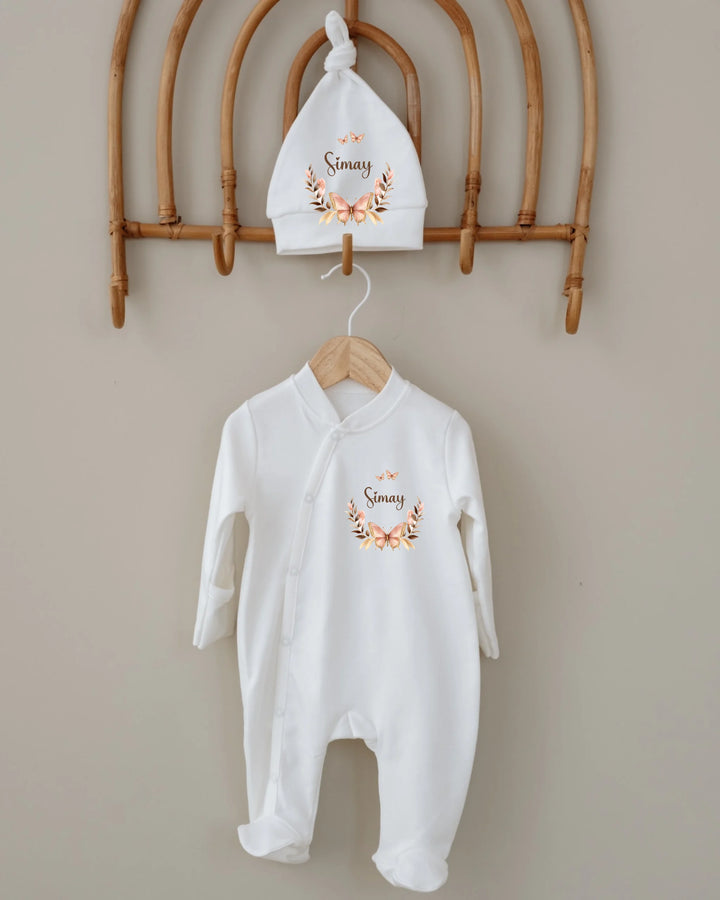 Gepersonaliseerde babyset met romper en mutsje, versierd met een vlinderkrans en de naam 'Simmy'.