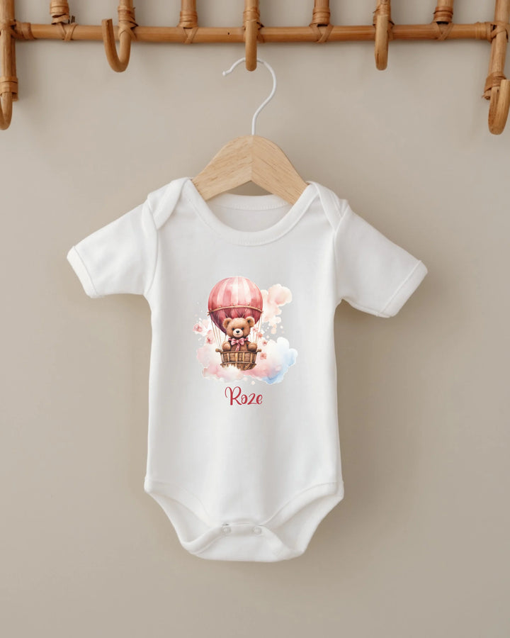 Witte romper met roze teddybeer in luchtballon en naam, ideaal voor pasgeboren meisjes.