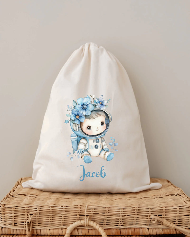 Gepersonaliseerde astronauten tas met naam Jacob en bloemen in blauw op een beige achtergrond.