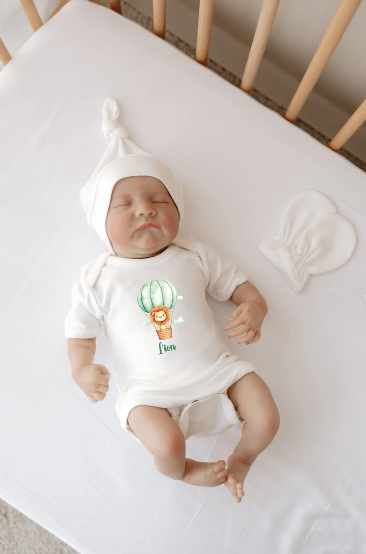 Gepersonaliseerde baby romper met leeuw in luchtballon en naam op een ledikantje