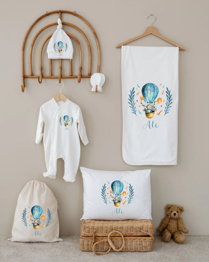 Gepersonaliseerde luchtballon newborn cadeauset met naam, katoenen romper, deken, kussen en muts in zachte kleuren.