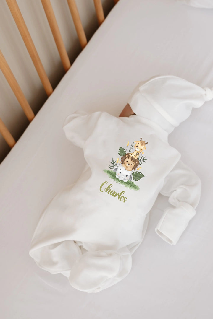 Gepersonaliseerde newborn romper met schattige safari dieren en de naam Charles op een bedje.