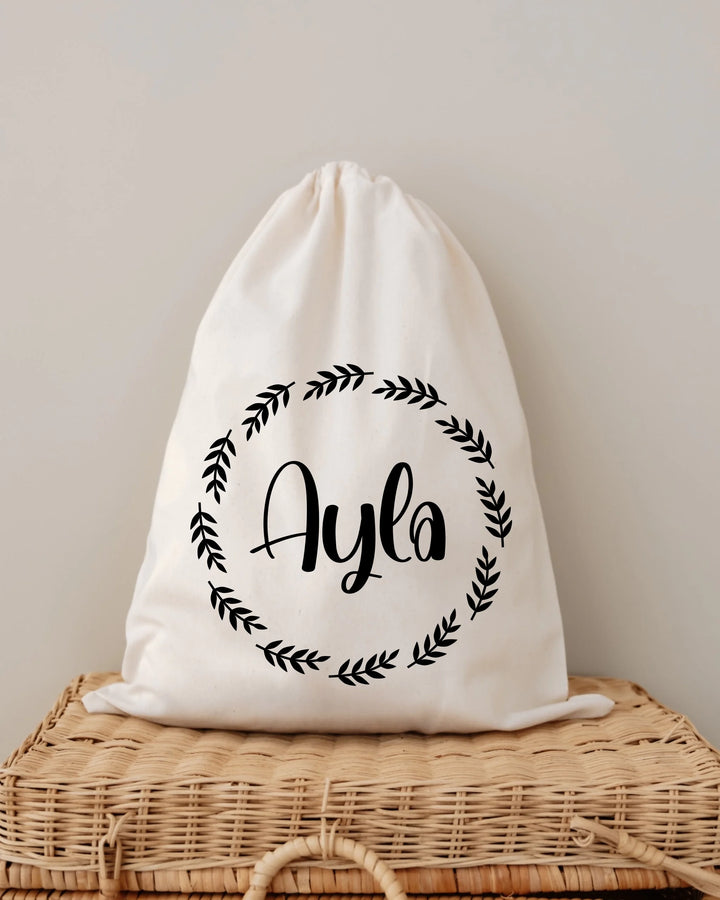 Gepersonaliseerde tas met naam 'Ayla' in een minimalistische krans op een neutrale achtergrond.