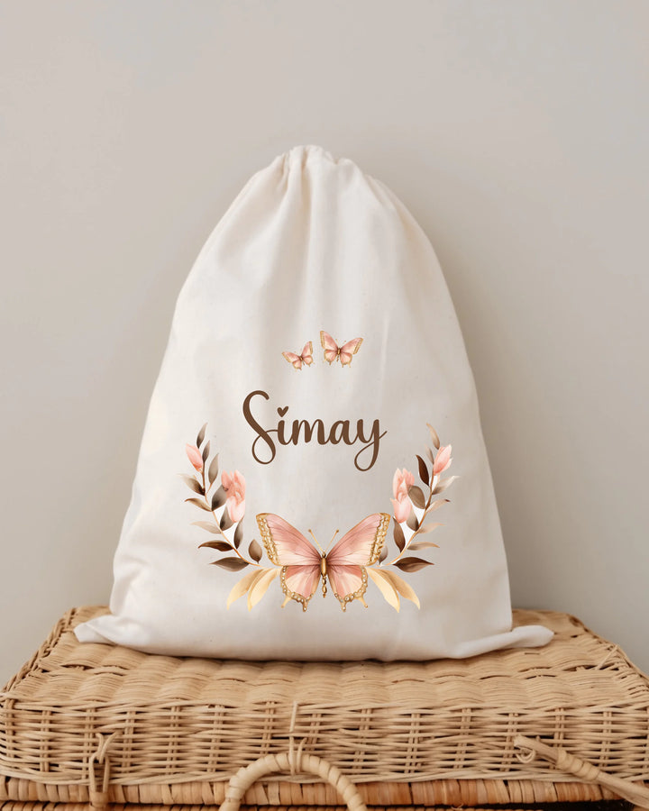 Gepersonaliseerd stoffen zakje met naam Simay en een roze vlinder en bloemen ontwerp.