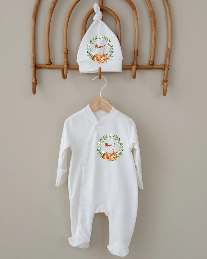 Gepersonaliseerde newborn kledingset met hertje in bloemenkrans en bijpassende muts, perfect voor baby's.