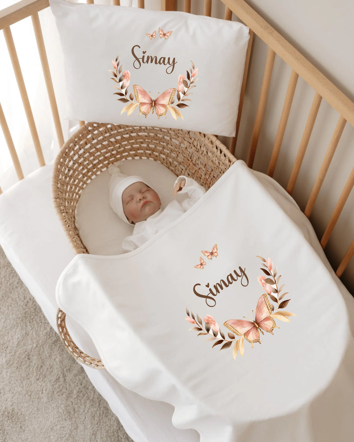 Gepersonaliseerde vlinder babyset met naam in wieg, perfect voor newborns, zachte kleuren en design.