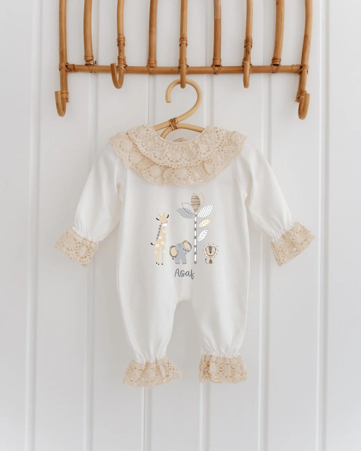 Wit katoenen babypakje met safari dieren en kanten details, ideaal voor newborns.