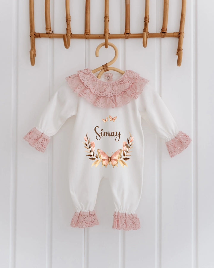Gepersonaliseerd kanten babypakje in wit met rozenkleurige details en vlinderprint voor meisjes.