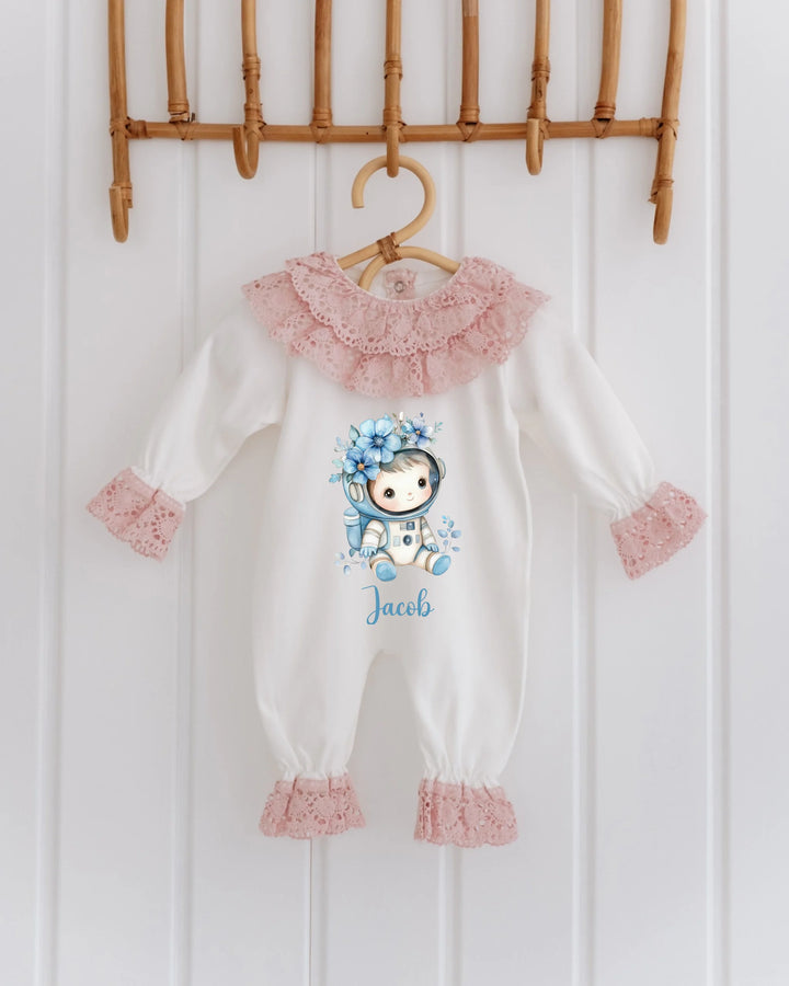 Gepersonaliseerd astronaut babypakje met naam Jacob, witte stof en roze kantdetails.