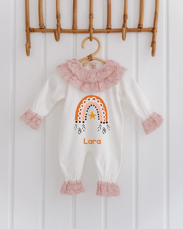 Kanten babypakje met regenboogprint en gepersonaliseerde naam Lara, geschikt voor meisjes, in warme aardetinten.