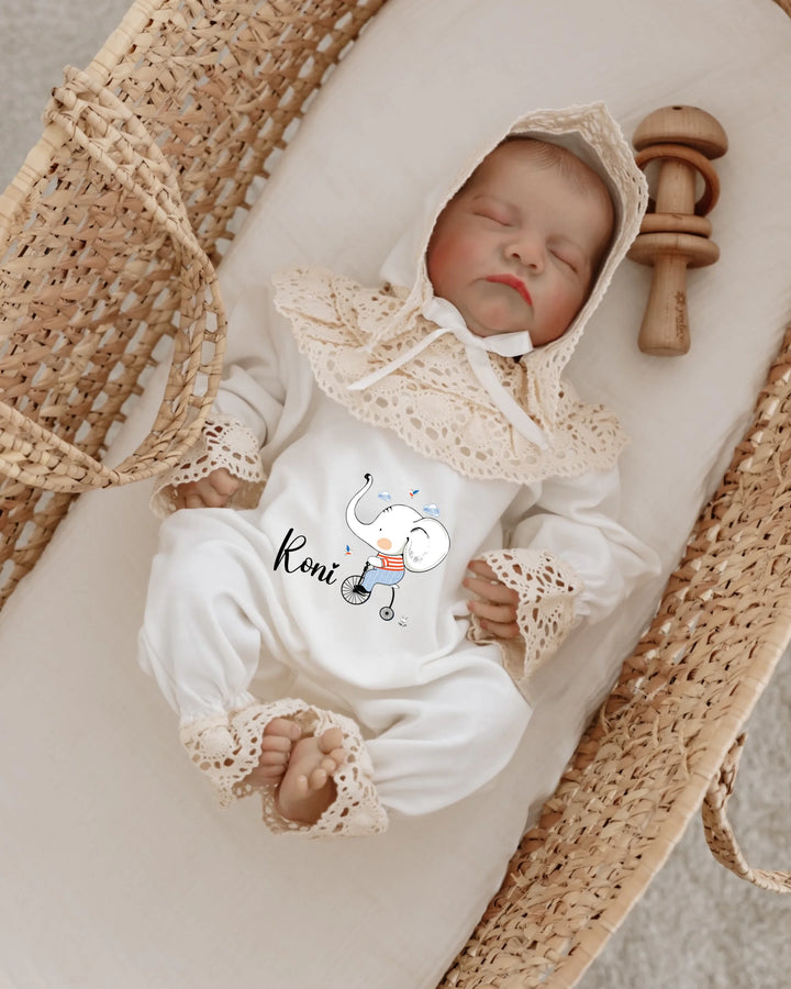 Olifant design babypakje met naam 'Roni' en kanten mutsje in een wieg.
