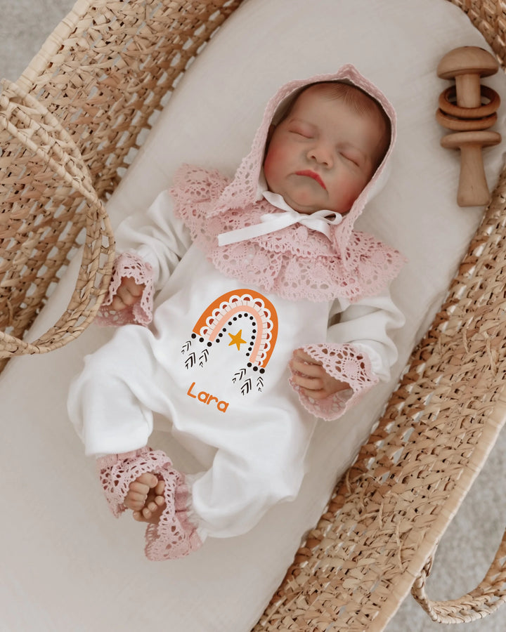 Zacht regenboog babypakje met kant en naam op een schattig meisje in een mand.