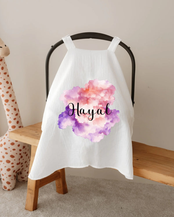 Gepersonaliseerde zonnekap met wolkenprint en naam 'Hayal' op een autostoel, perfect voor baby's.