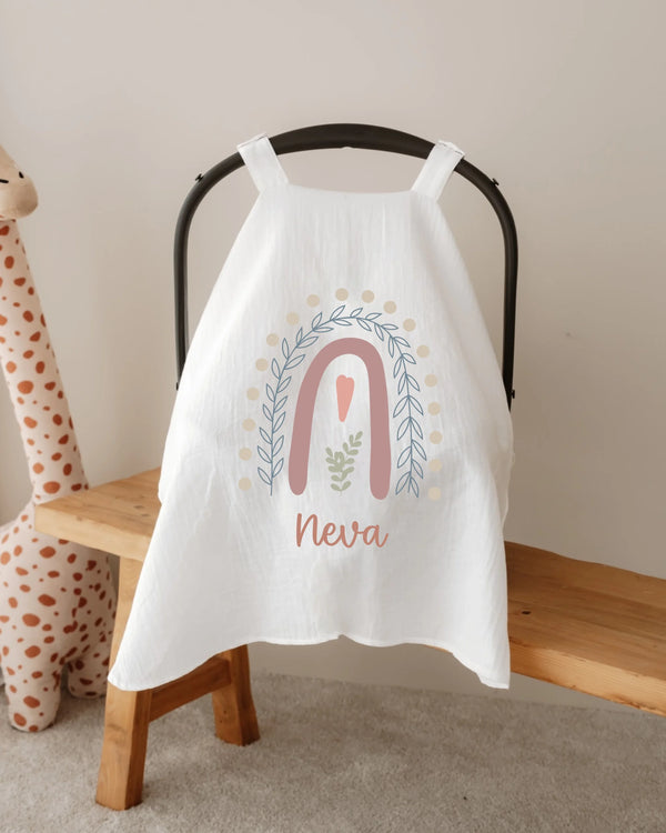 Gepersonaliseerde witte zonnekap voor autostoel met regenboog en naam Neva, perfect voor pasgeboren meisjes.