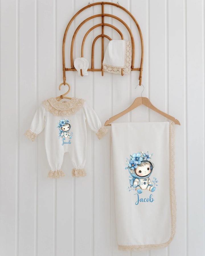 Personalized newborn astronaut set featuring a romper, blanket, and accessories with lace details, ideal for babies.