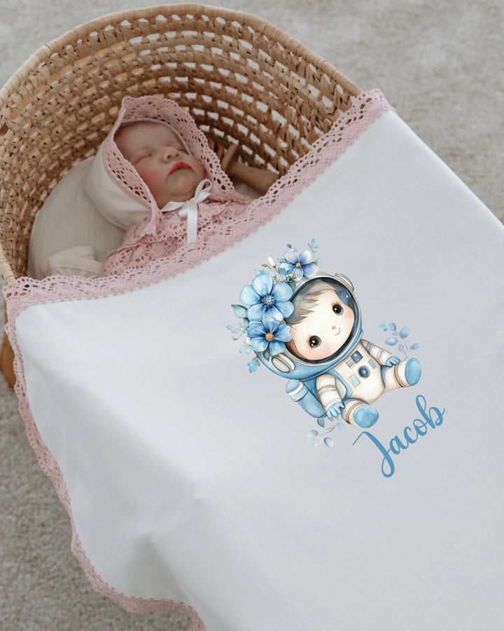 Newborn baby sleeping under astronaut-themed personalized blanket with lace, featuring the name Jacob.