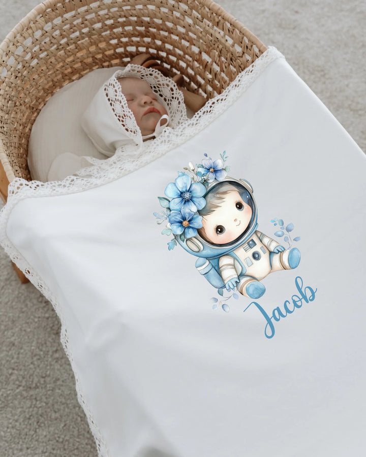 Newborn baby sleeping in a basket, wrapped in an astronaut-themed blanket personalized with the name Jacob.