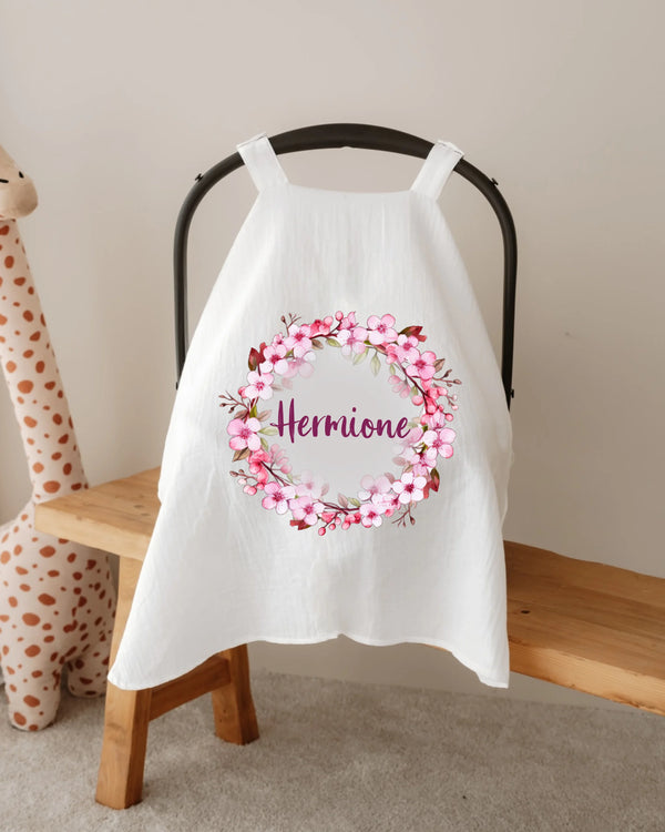 Gepersonaliseerde hydrofiele zonnekap met roze bloemenkrans en naam, ideaal voor baby's autostoel.