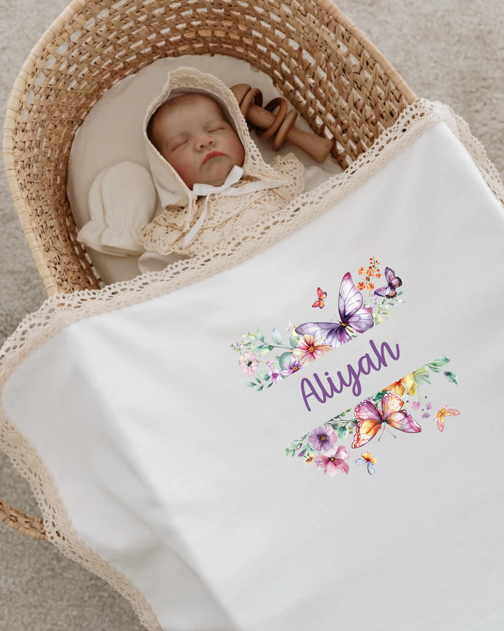 Newborn baby girl Aliyah sleeping in a cozy bassinet, wrapped in a floral and butterfly themed blanket.