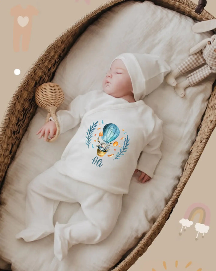 Een baby in een zacht, biologisch katoenen outfit met luchtballonprint, rustend in een houten wieg.