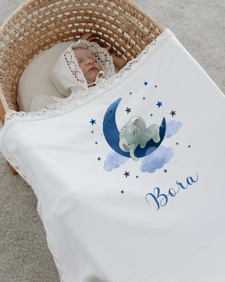 Newborn girl sleeping under personalized blanket with blue elephant design, stars, and moon, named Bora.
