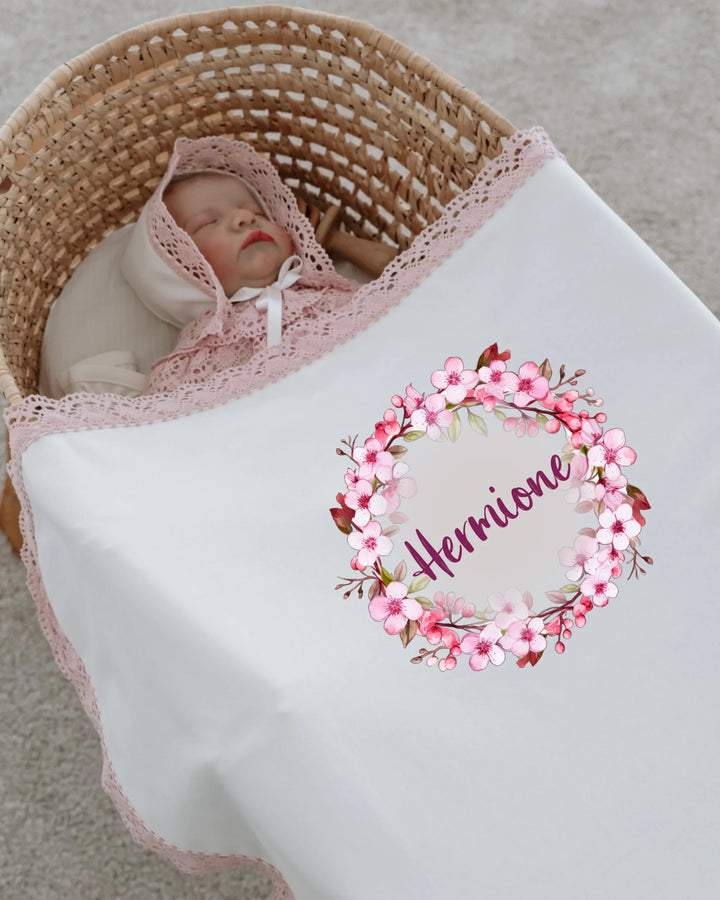 Newborn girl sleeping in a floral personalized blanket with lace trim featuring the name Herrione.