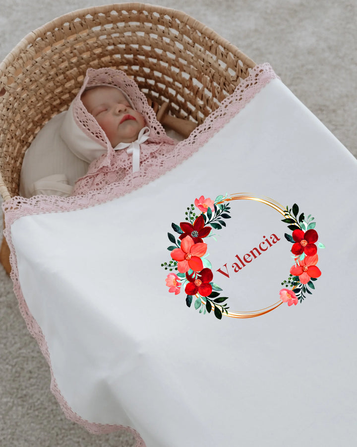 Newborn girl sleeping in a personalized floral blanket with lace trim, featuring the name Valencia.