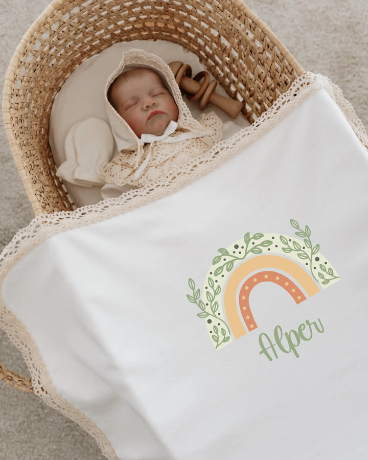 Slaapende baby in een mand met een geboortepakje en een regenboogdesign met naam, in zachte natuurlijke kleuren.