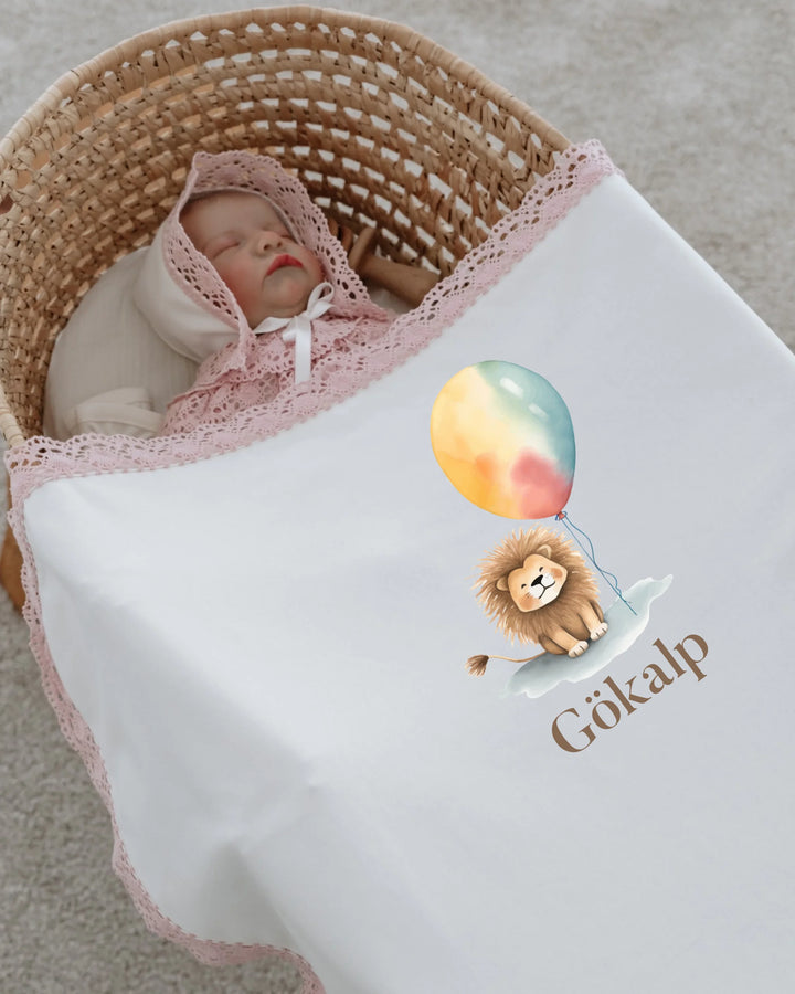 Newborn girl wrapped in a blanket with a cute lion and balloon design, personalized for a magical start.