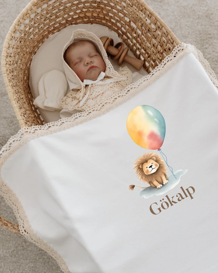 Slaapbaby in een wieg met een knuffel en een dekentje met een leeuw en een ballon er op.