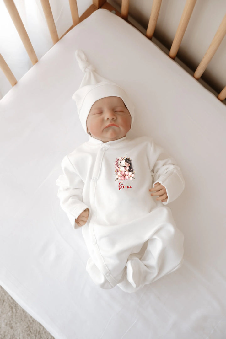 Witte baby boxpakje met naam en eenhoorn ontwerp, perfect voor pasgeboren meisjes in ledikant.