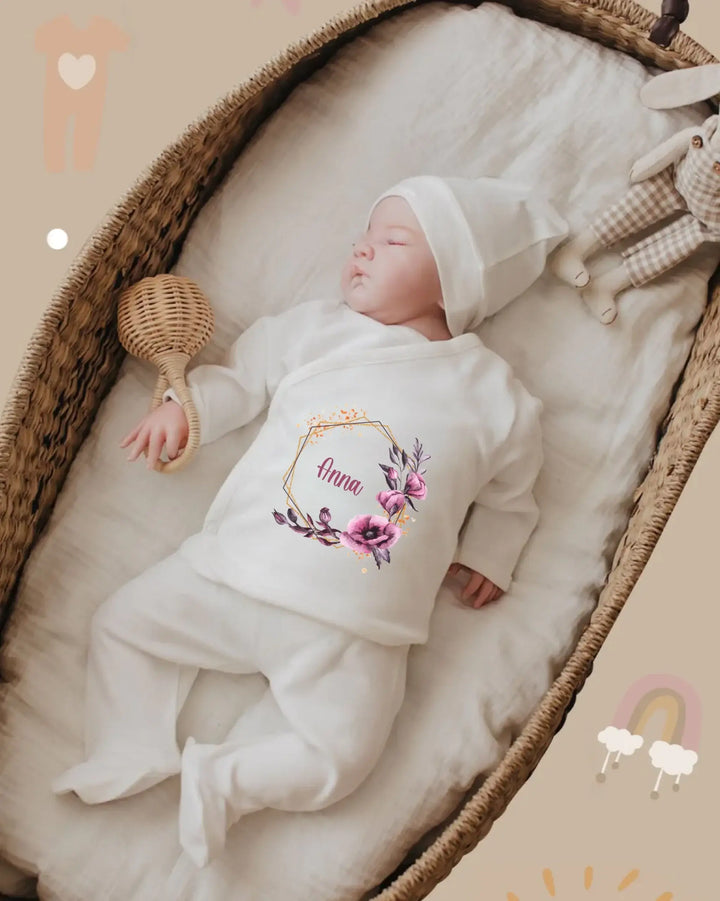Schattige baby in gepersonaliseerde witte outfit met bloemenprint en naam, vredig slapend in kinderbedje.