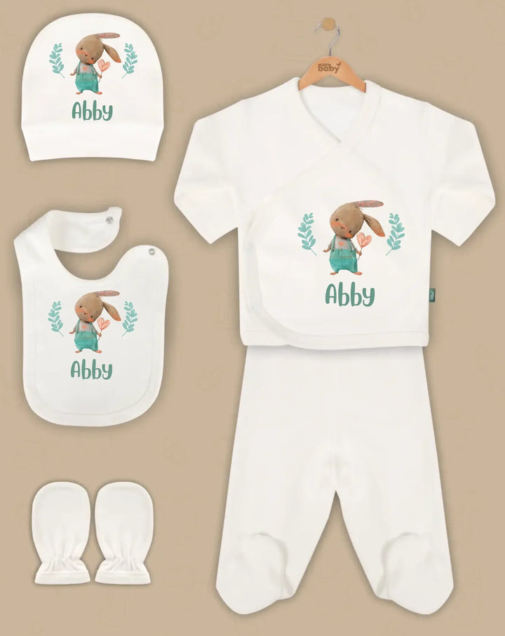 Gepersonaliseerde babykleding set met schattige konijnenafbeelding, inclusief muts, truitje, broek, slab en wanten.