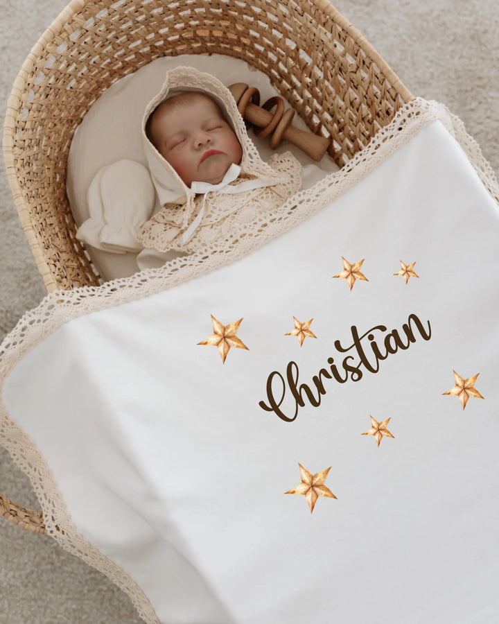 Newborn baby named Christian sleeping in a woven basket, wrapped in a blanket featuring a star design.